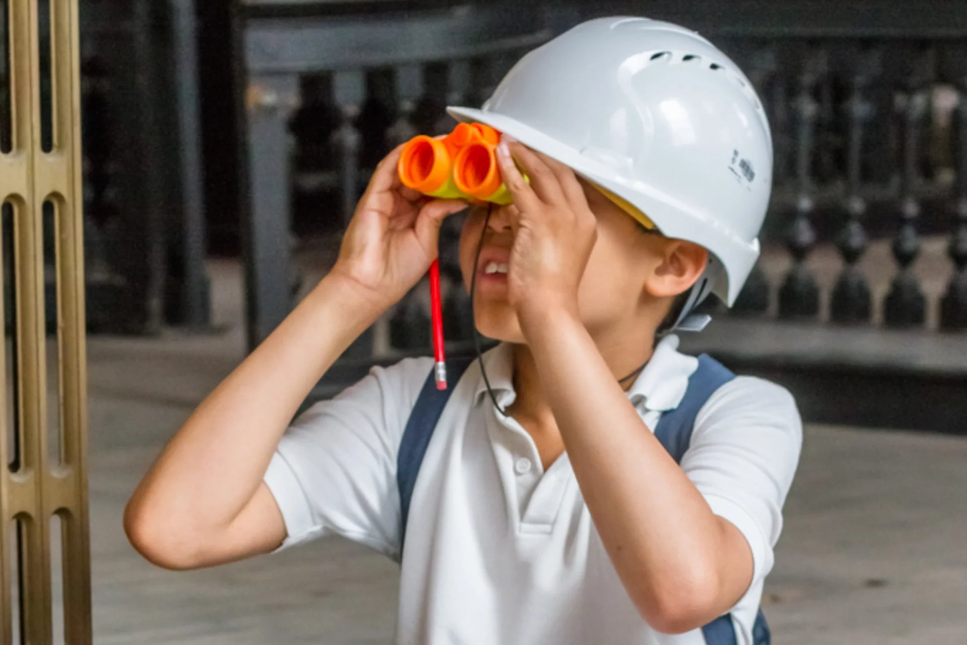 Child exploring CCT's church in Sunderland whilst sitting crossed legged on the floor with a clipboard and toy binoculars.