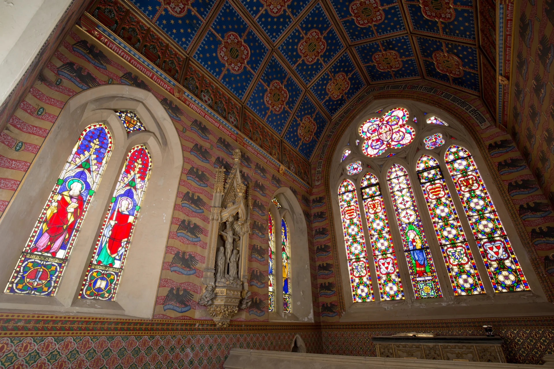 Chapel decorated with colourful stencilling and stained-glass.