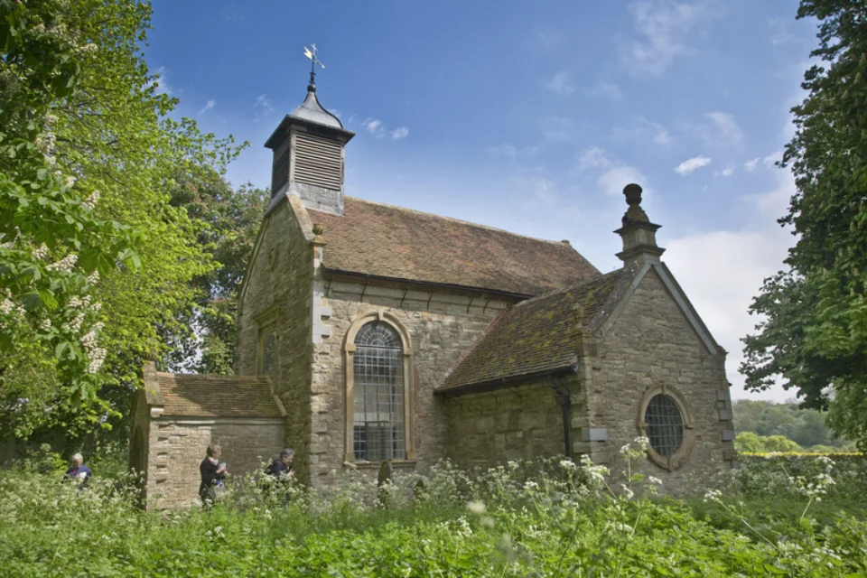 The exterior of the church looks Georgian and seen within the wooded churchyard.