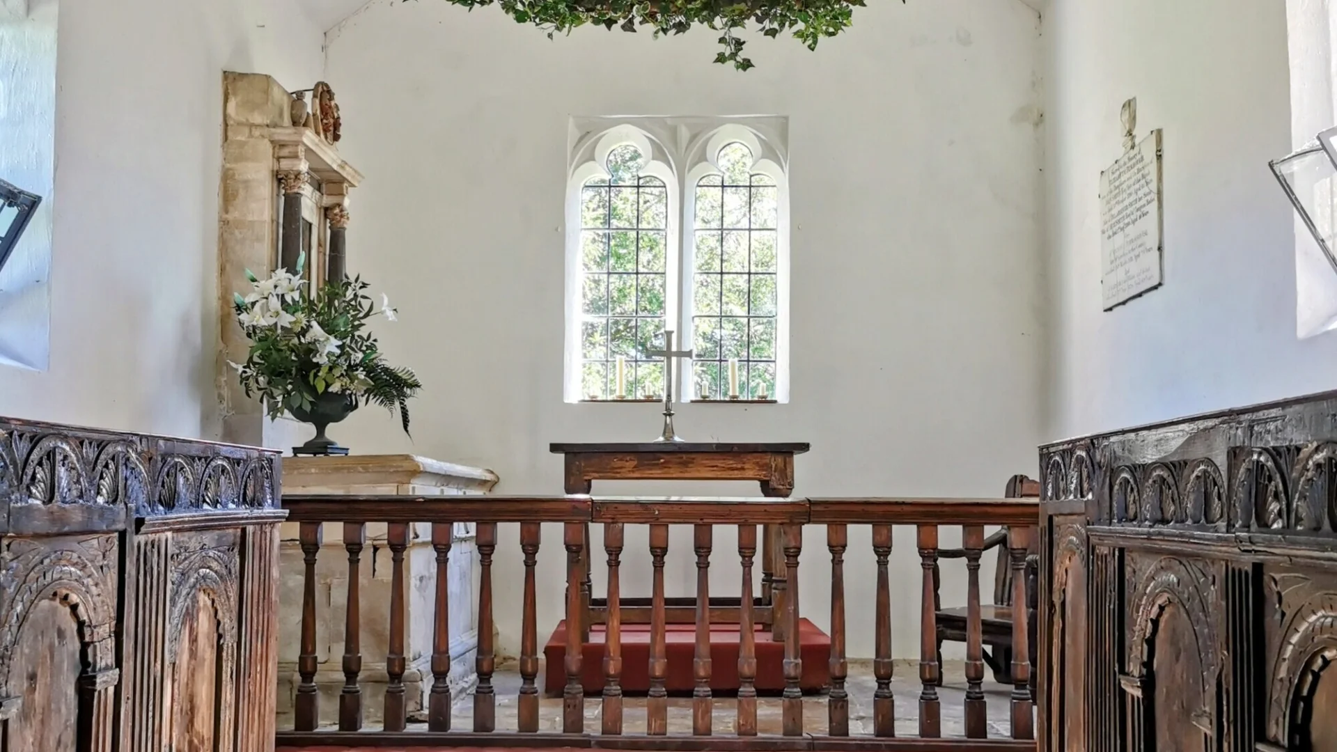 The chancel of Alton priors, featuring historic Jacobean choir stalls and displays of artificial greenery. The choir stalls in the chancel are the only surviving pews in this church.
