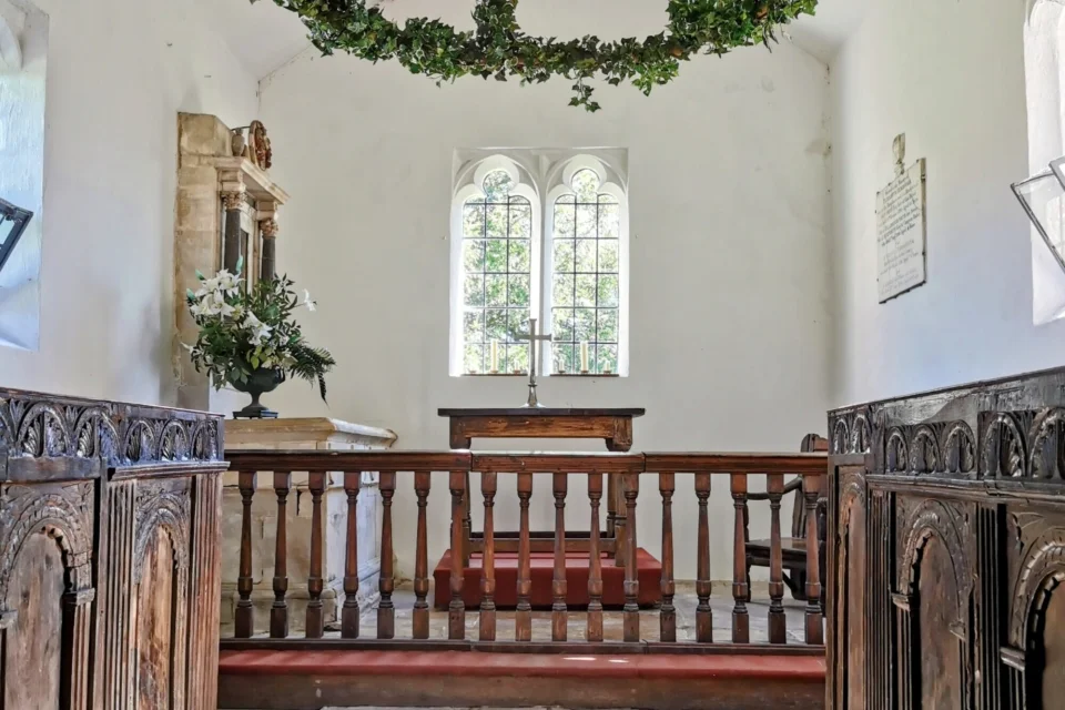 The chancel of Alton priors, featuring historic Jacobean choir stalls and displays of artificial greenery. The choir stalls in the chancel are the only surviving pews in this church.