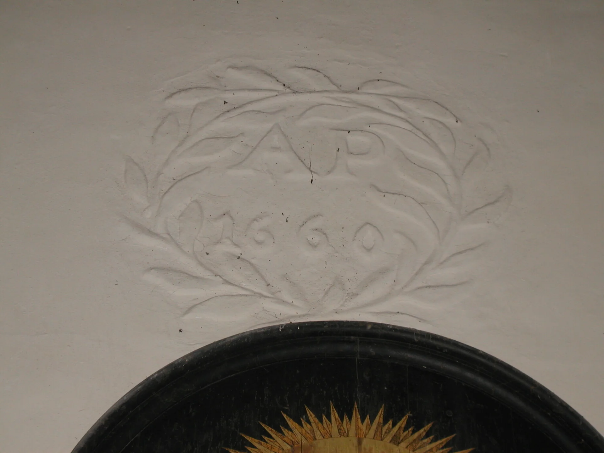 The initials A. P. and below the number 1660 framed by a laurel wreath all moulded in white plaster.