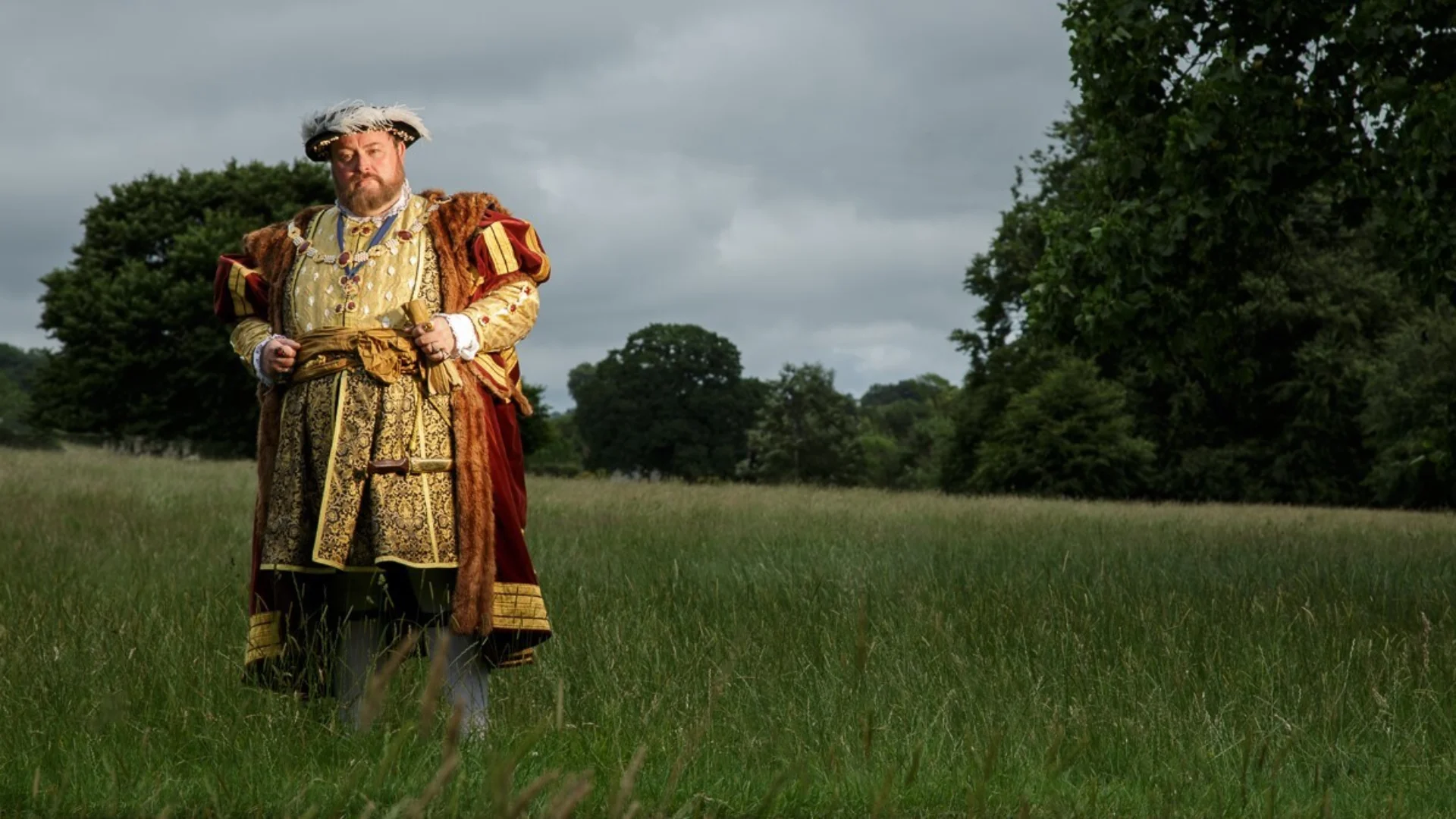 Actor dressed as Henry VIII standing in a field