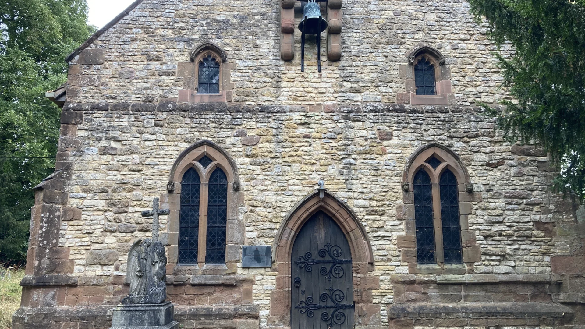 West end of stone church showing door and chiming bell