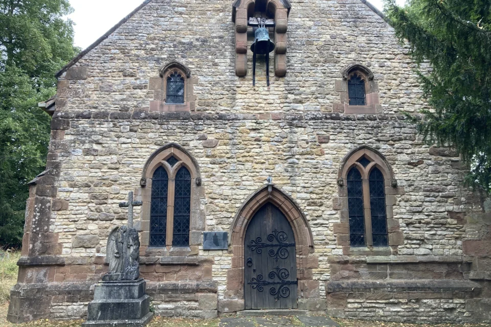 West end of stone church showing door and chiming bell