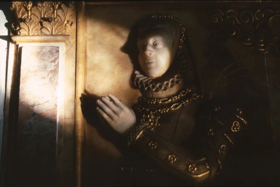Relief effigy of Lady Jane Lumley, dressed in a ruff and bonnet, kneeling in prayer decorated with gold details.