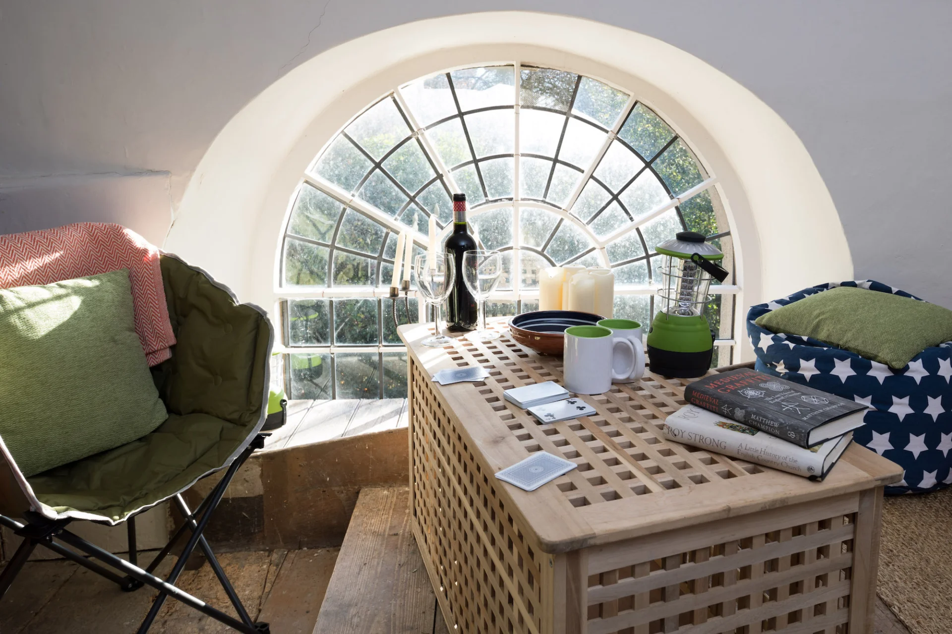 Champing set up with a chair and bean bag sitting area with little pillows table with wine glass and a large wine.