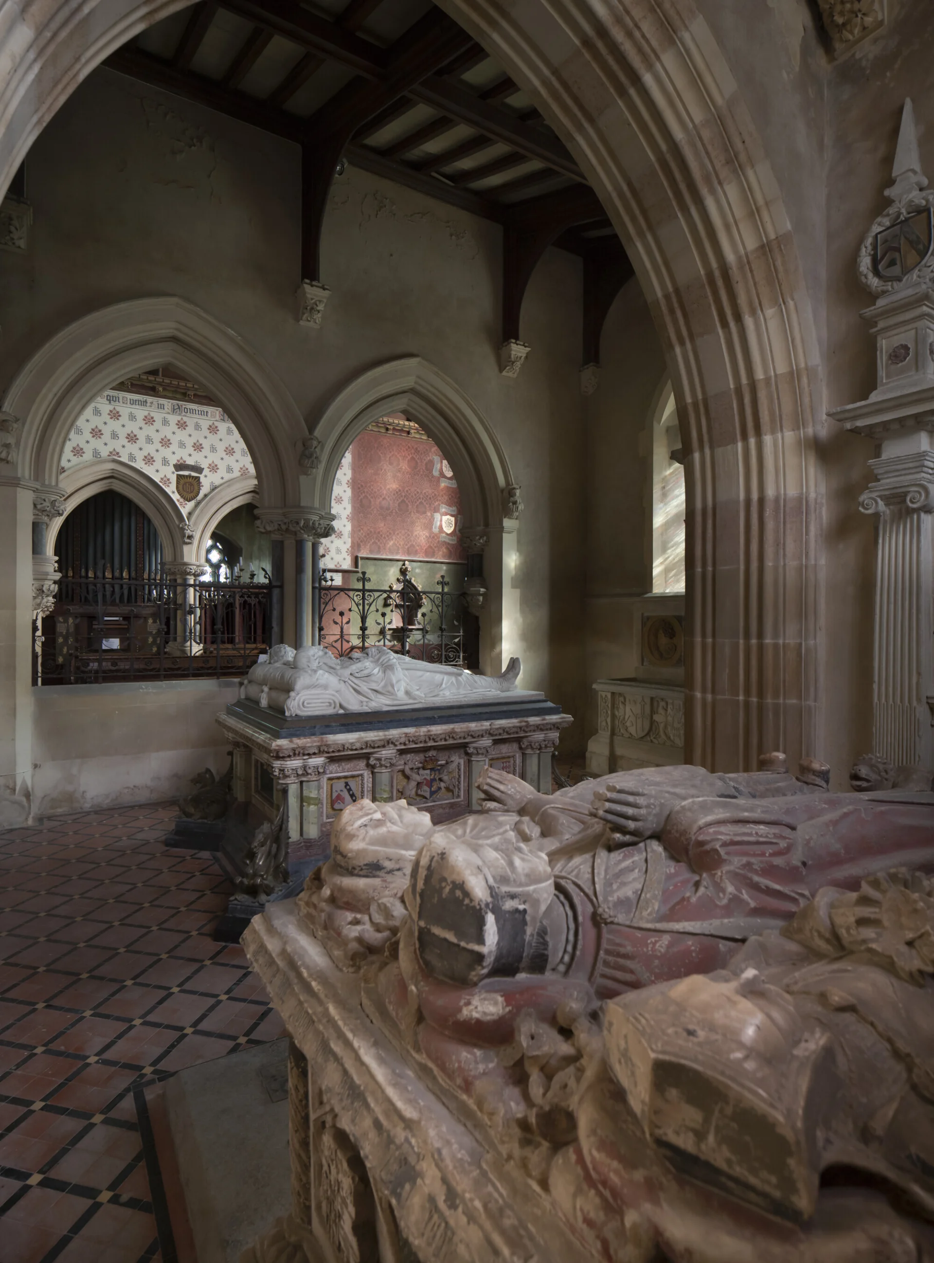 View of the interior of the Brudenell Chapel at St. Peter's, Deene. In the front can be seen the recumbent effigies of Sir Robert and his two wives all painted in Tudor fashion. At the back we can see two white marble or alabaster recumbent effigies on top of a chest tomb.