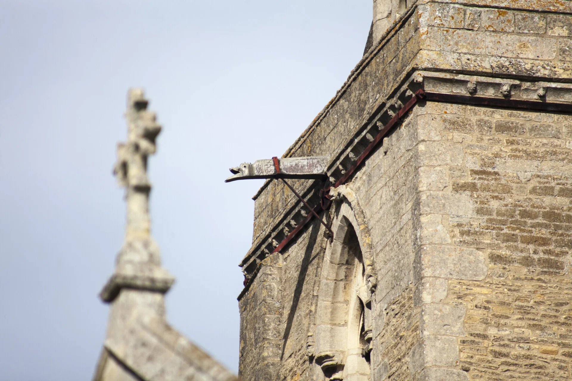 Exterior detail of St. Peter's, Deene showing part of a tower with gargoyle.