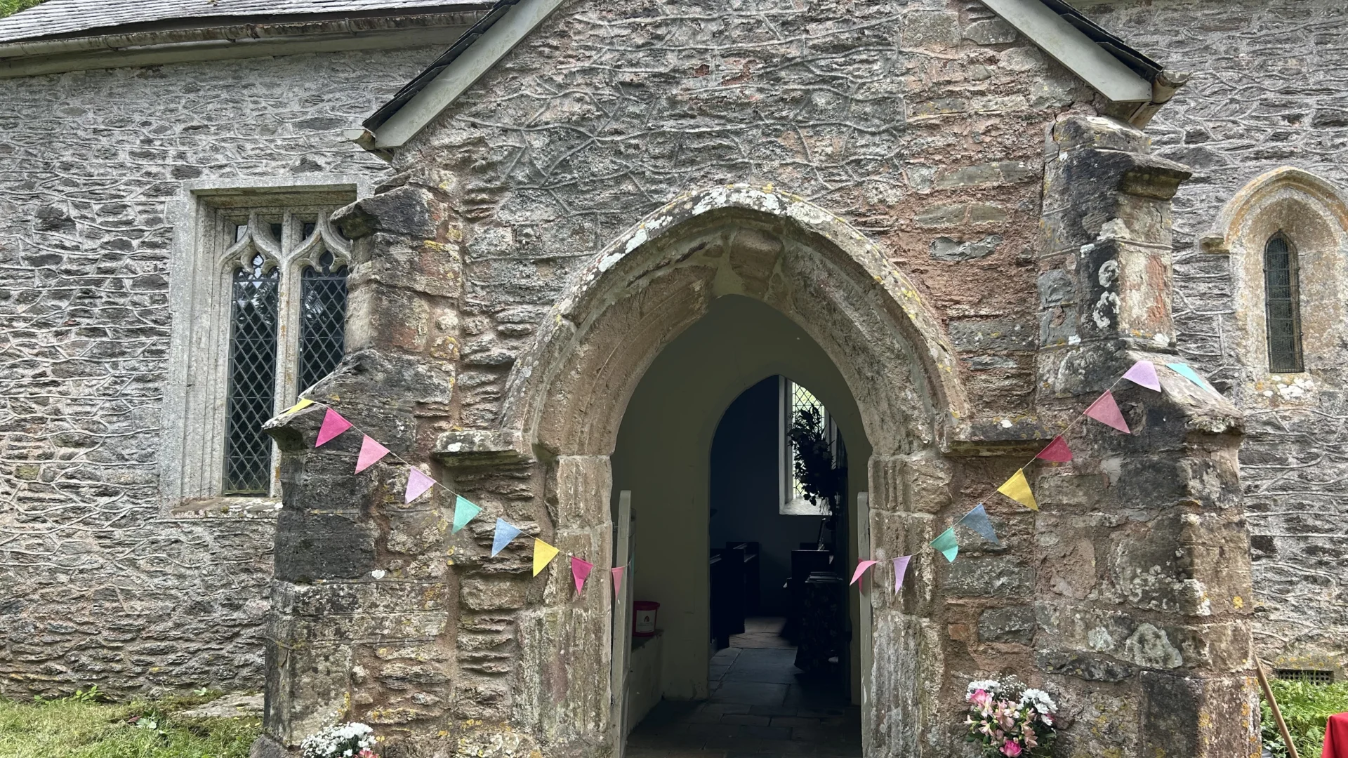 Entrance to Elworthy chruch showing coloured flags and flowers