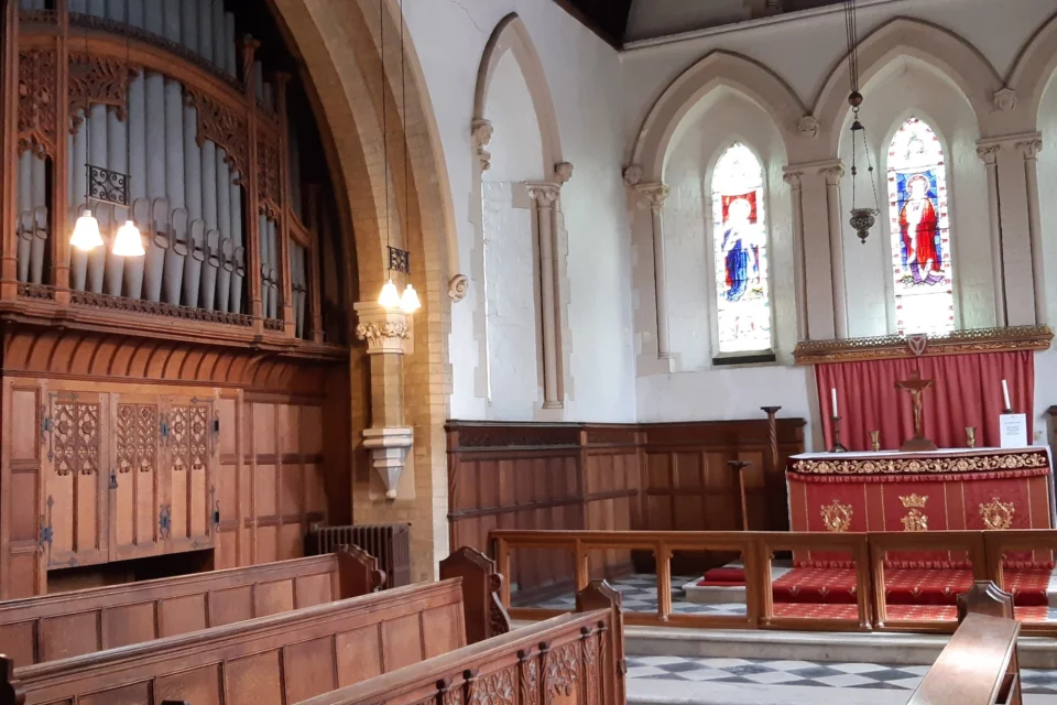 Interior with organ, decorative light wooden pews and stained glass windows