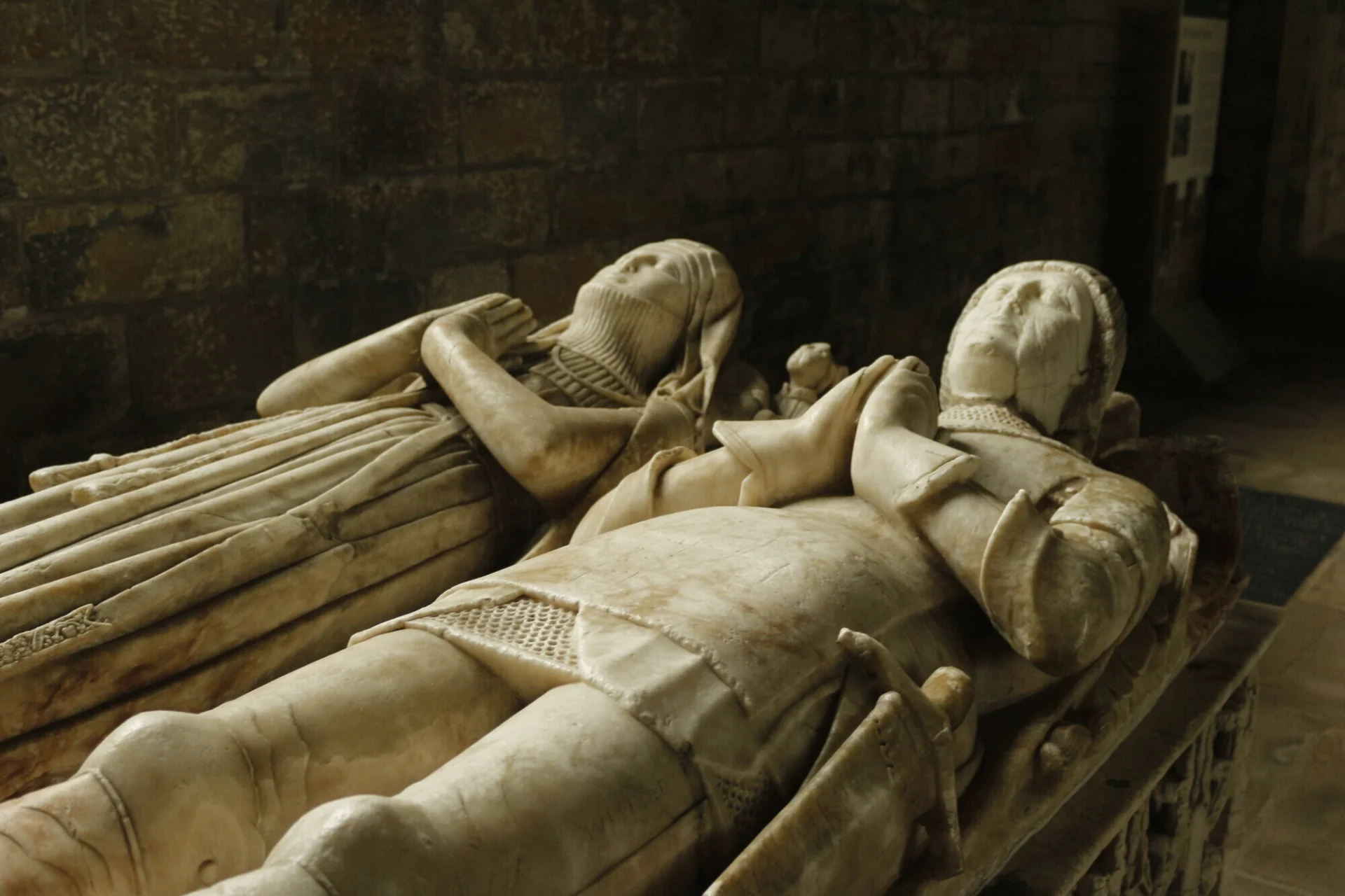 Reclining effigies of a man and a woman, hands clasped in prayer.