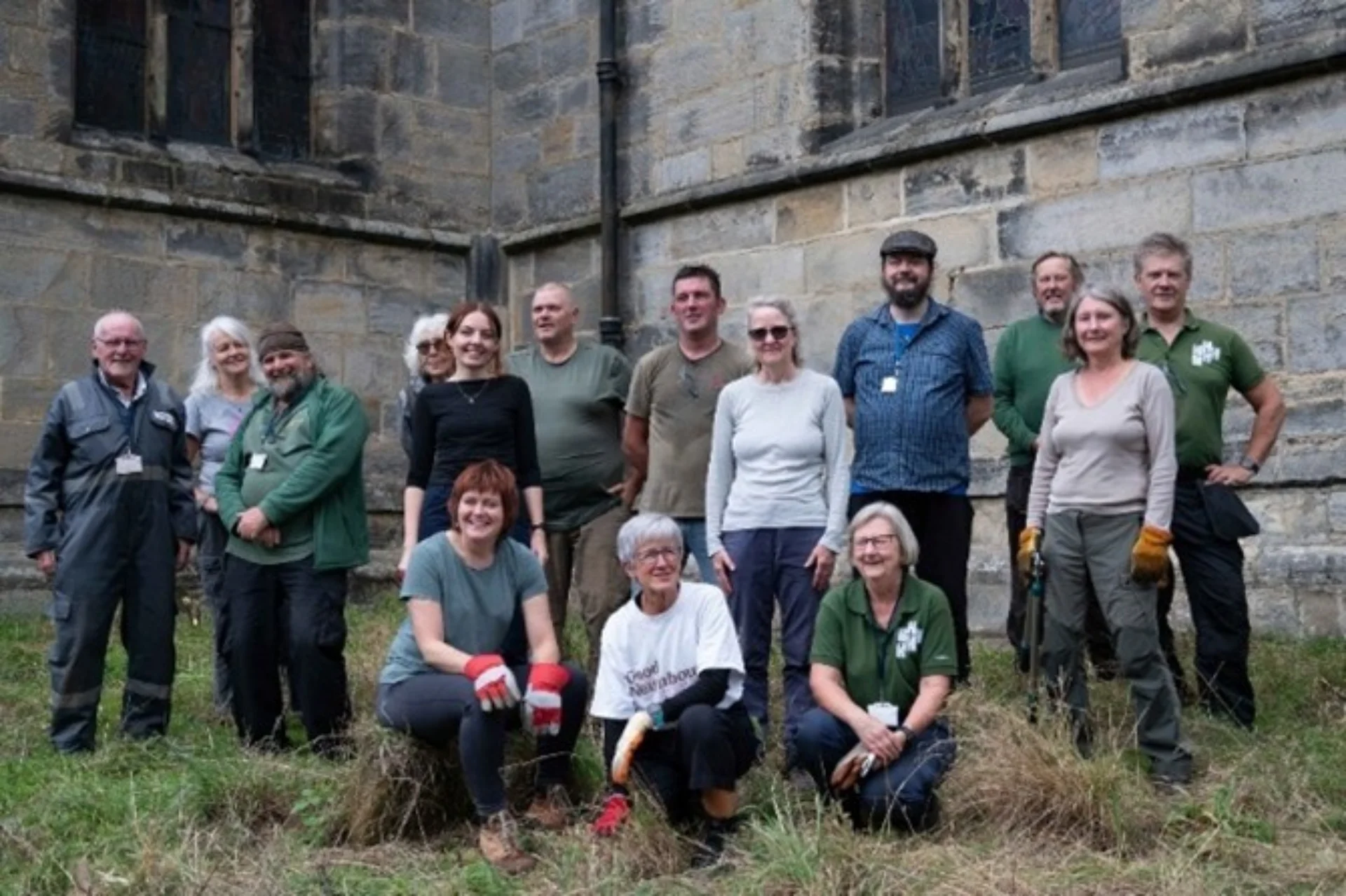 Team of volunteers standing in front of All Saints' Church, posing for a group shot following a day of gardening