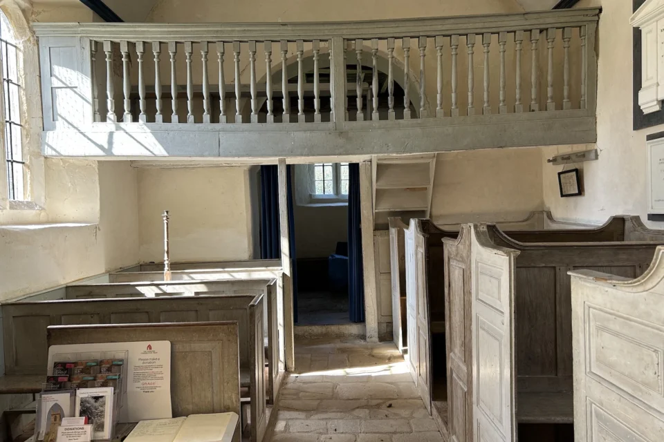 light blue balcony across the width of this short church over the entrance, tall and short Georgian pews below