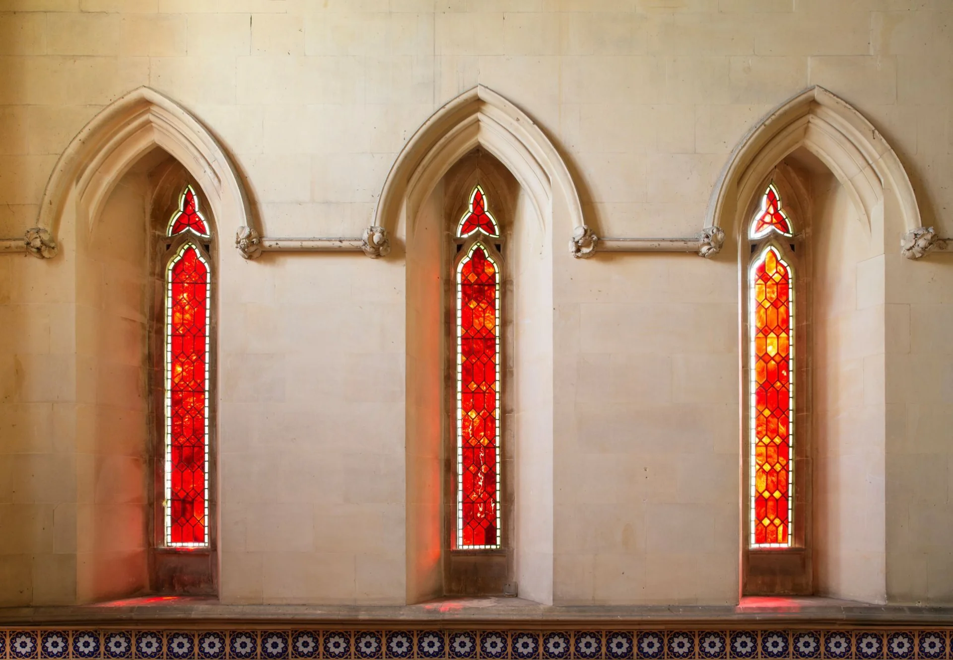Three lancet windows glow with bright red glass.