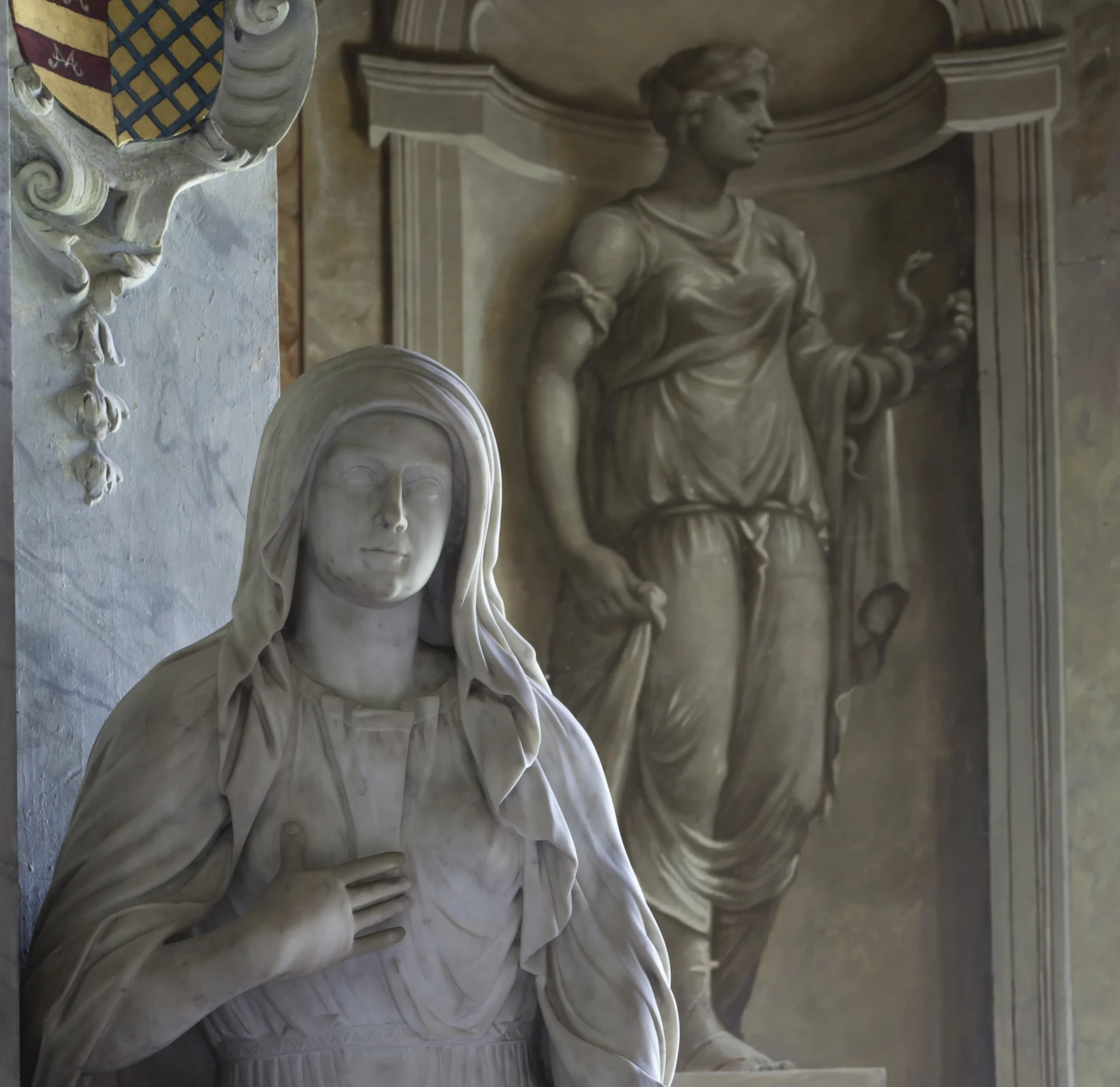 statue of a woman in robes in front of a wall painting of a woman in robes in an alcove