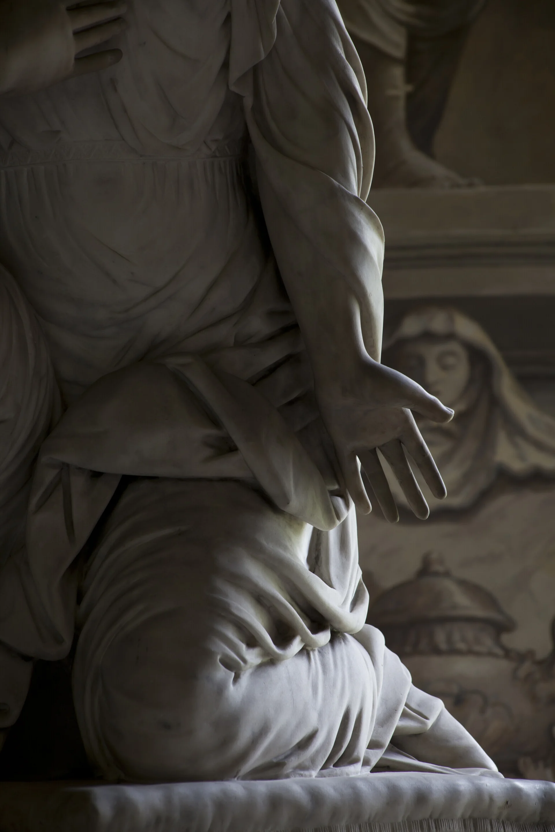outstretched arm of a beautiful white marble sculpture of a robed woman