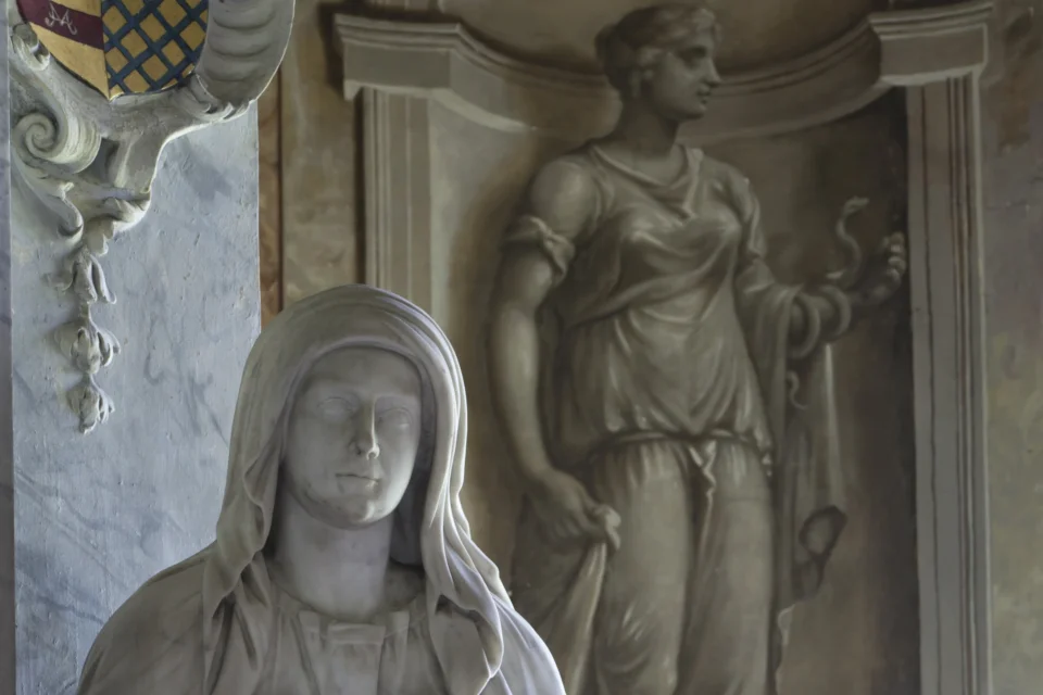 statue of a woman in robes in front of a wall painting of a woman in robes in an alcove