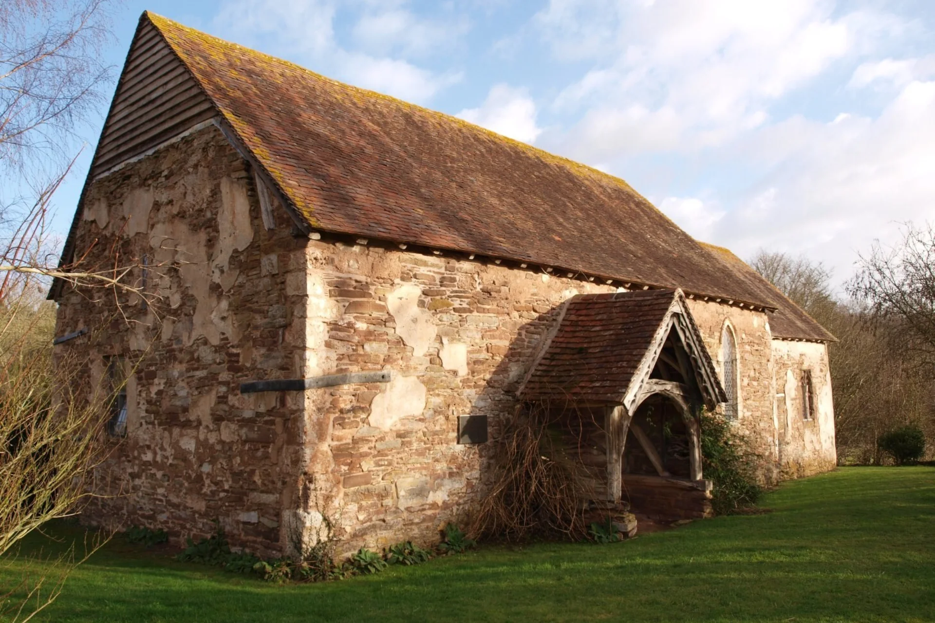 Simple Norman church exterior with wonderful oak porch is weathered to a beautiful silver-grey