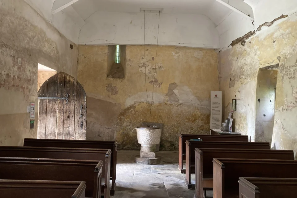 Interior of St Michael's Church in Michealchurch showing door, font and wall paintings.