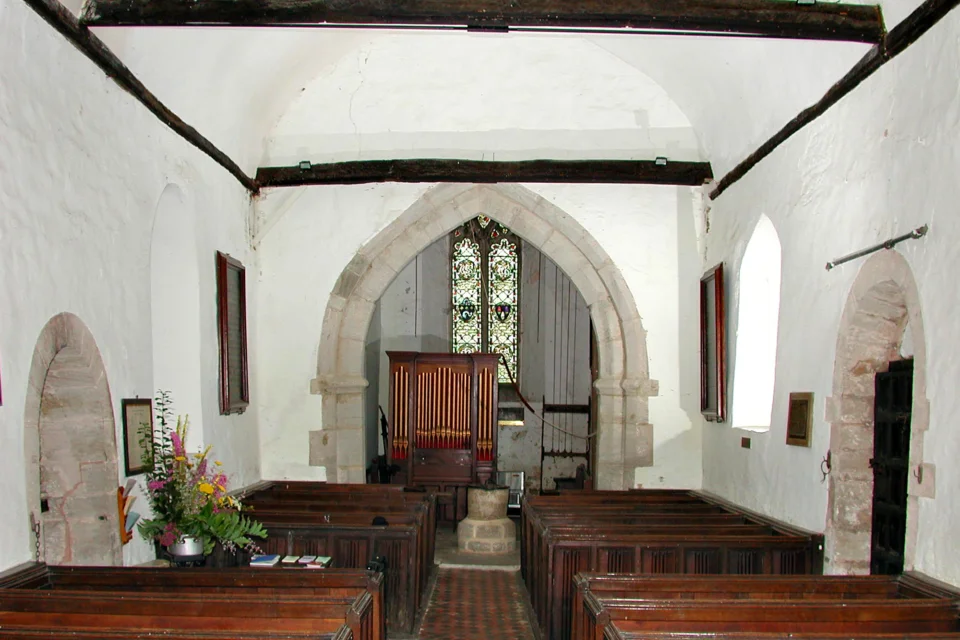 Norman white washed interior, with large wooden cross beams, little Georgian Organ and sixteenth-century pews
