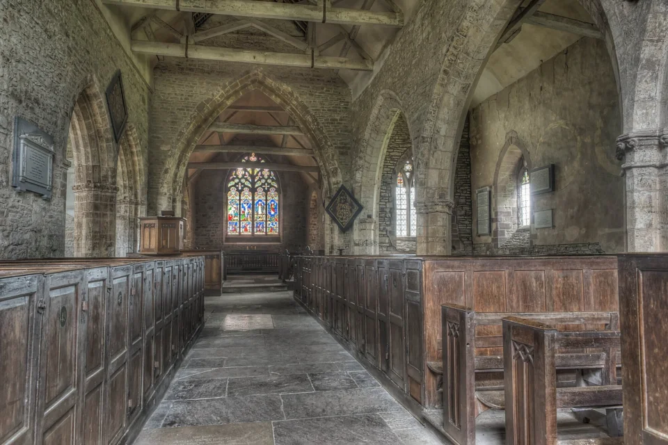 Interior view of the atmospheric church with a large stained glass window above the altar at the end of the aisle