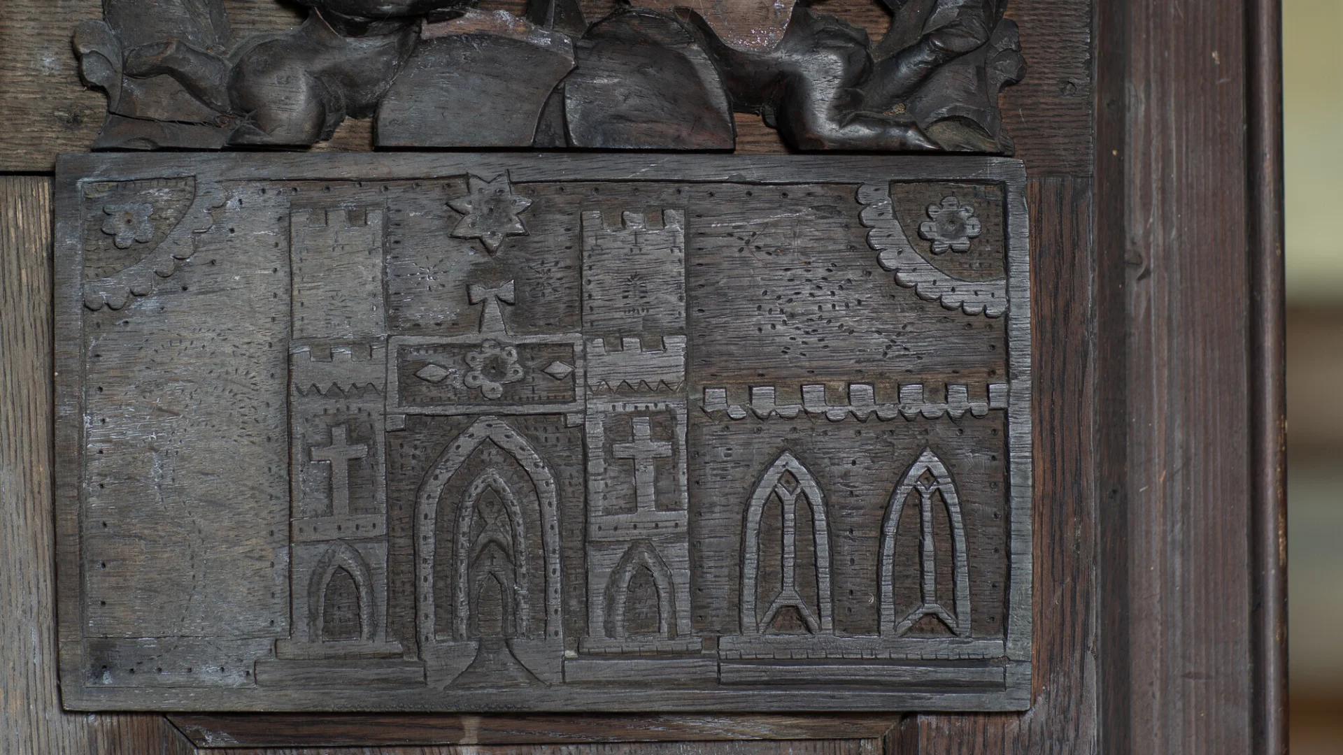Jacobeans style wooden panelling depicting a castle and windows.