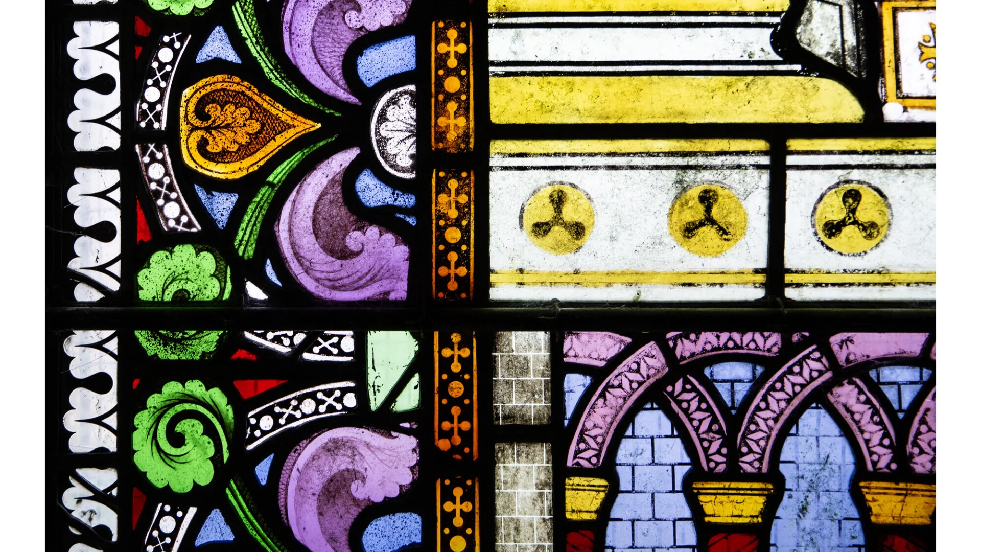 A vibrant and beautiful section of stained glass, with purples, blues, greens, gold and reds.