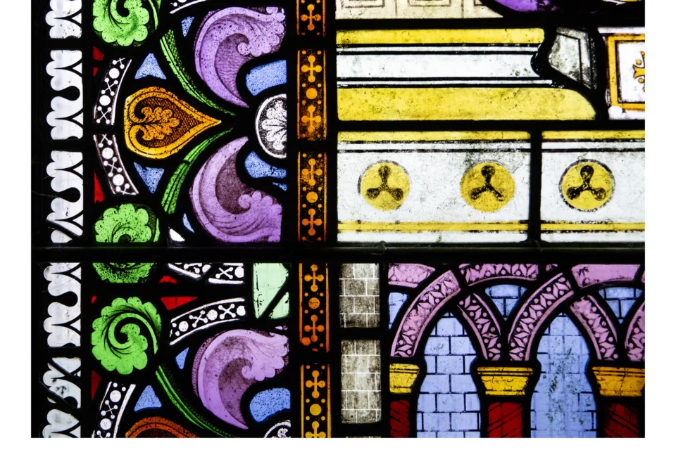 A vibrant and beautiful section of stained glass, with purples, blues, greens, gold and reds.