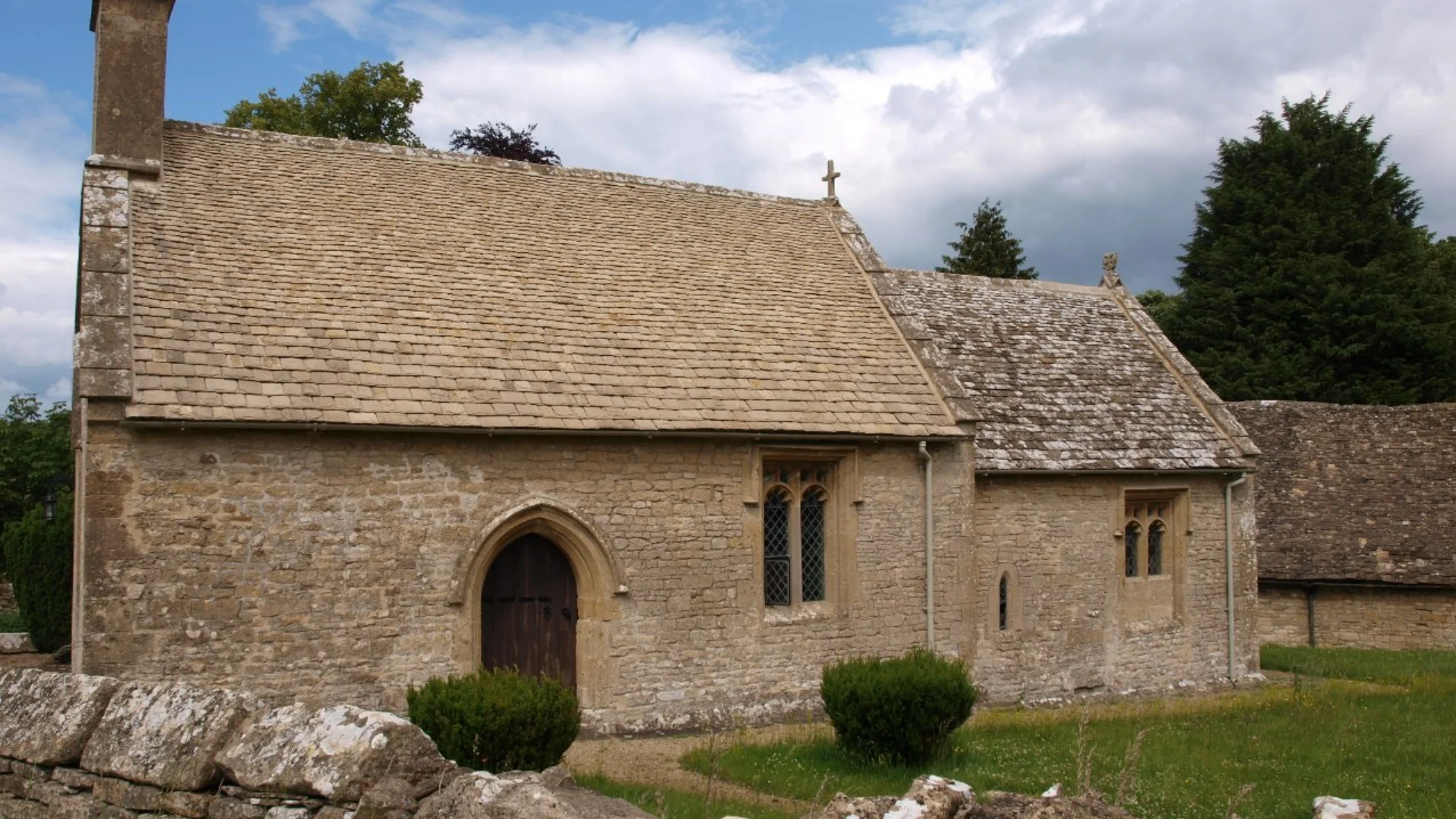 A quaint little stone church with a stone wall protecting its church yard.