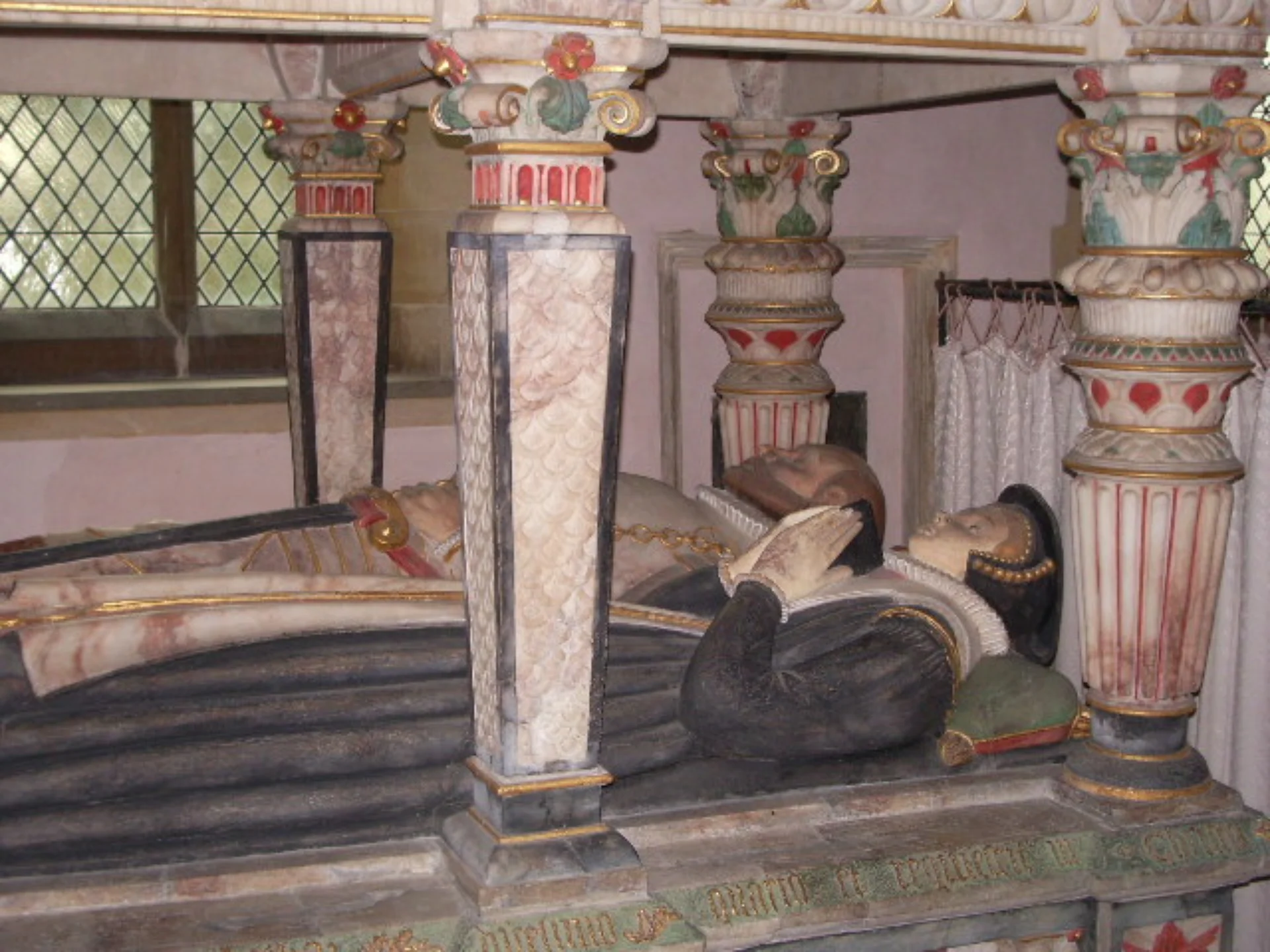 Sir Thomas and Lady Faiths' effigies recumbent on a tomb resembling a lavishly decorated and painted 6-poster bed.