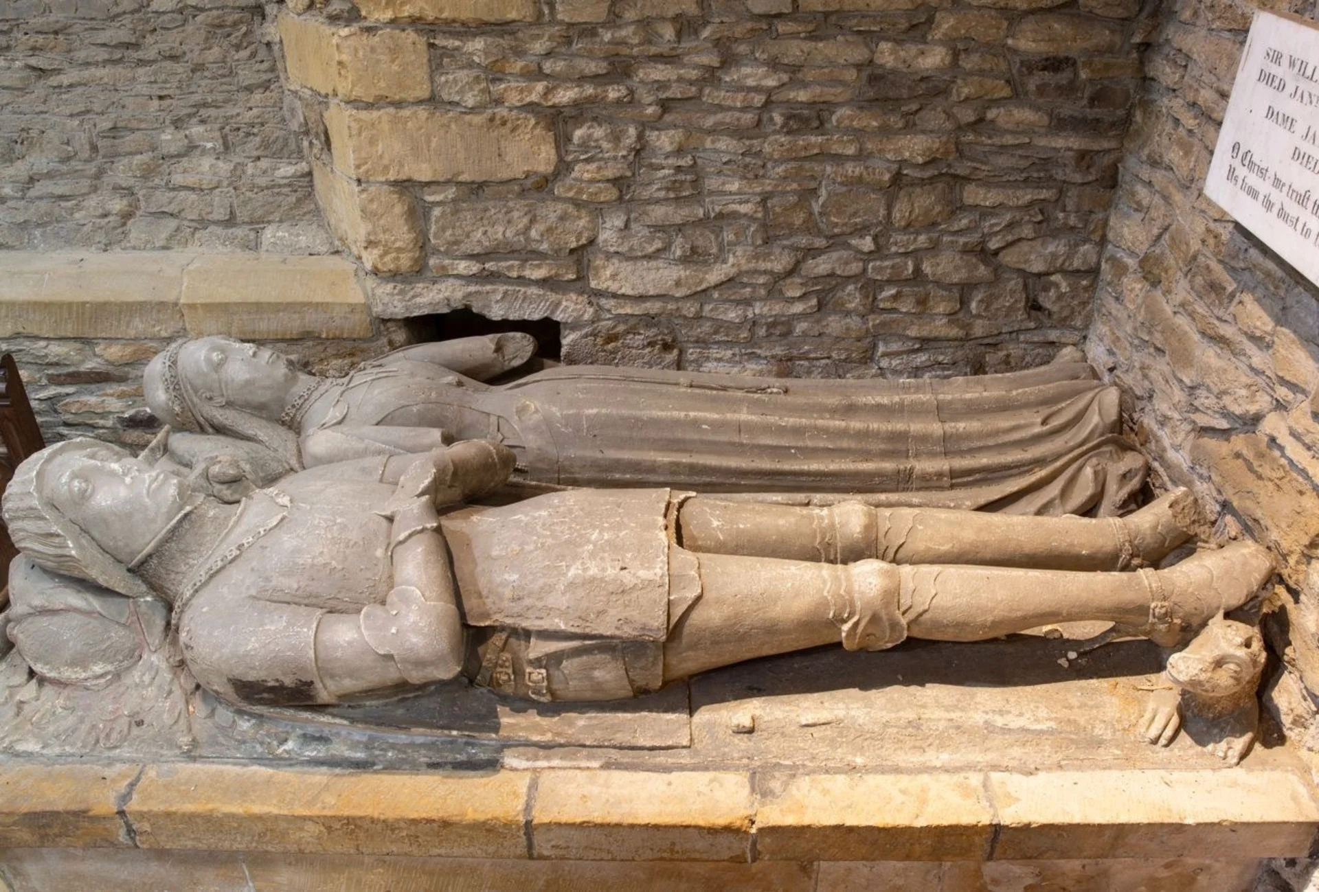 Tomb chest with two recumbent effigies of a man and woman in 16th Century clothing. He wears armor, she wears a dress.