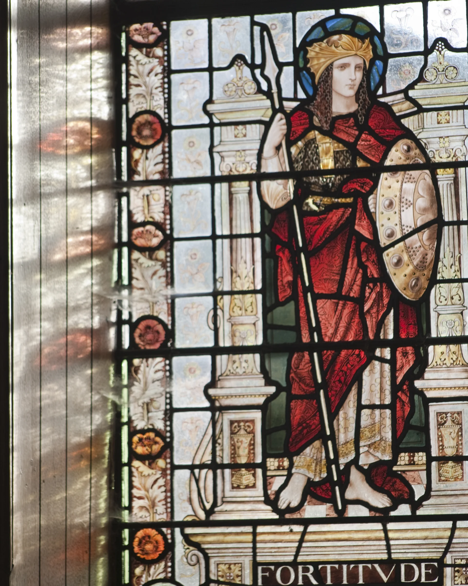 stained glass window with a female embodiment of Fortitude, depicted  in classical armor with shield and spear