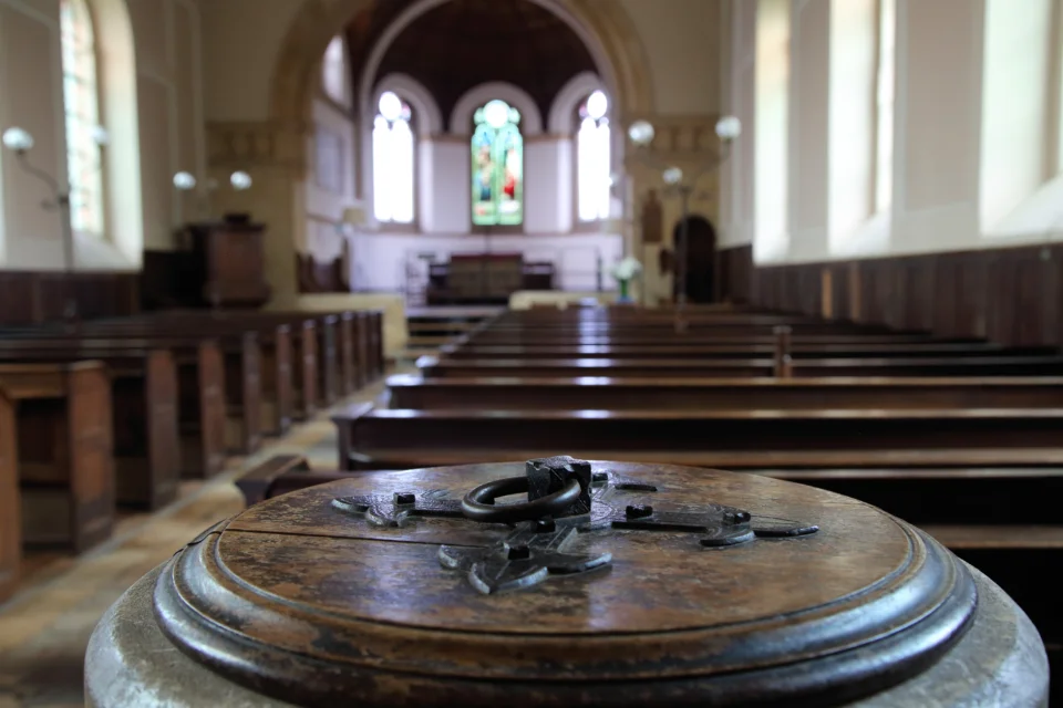 Close up of Baptismal font's carved lid with interior of the church blurred in the back ground