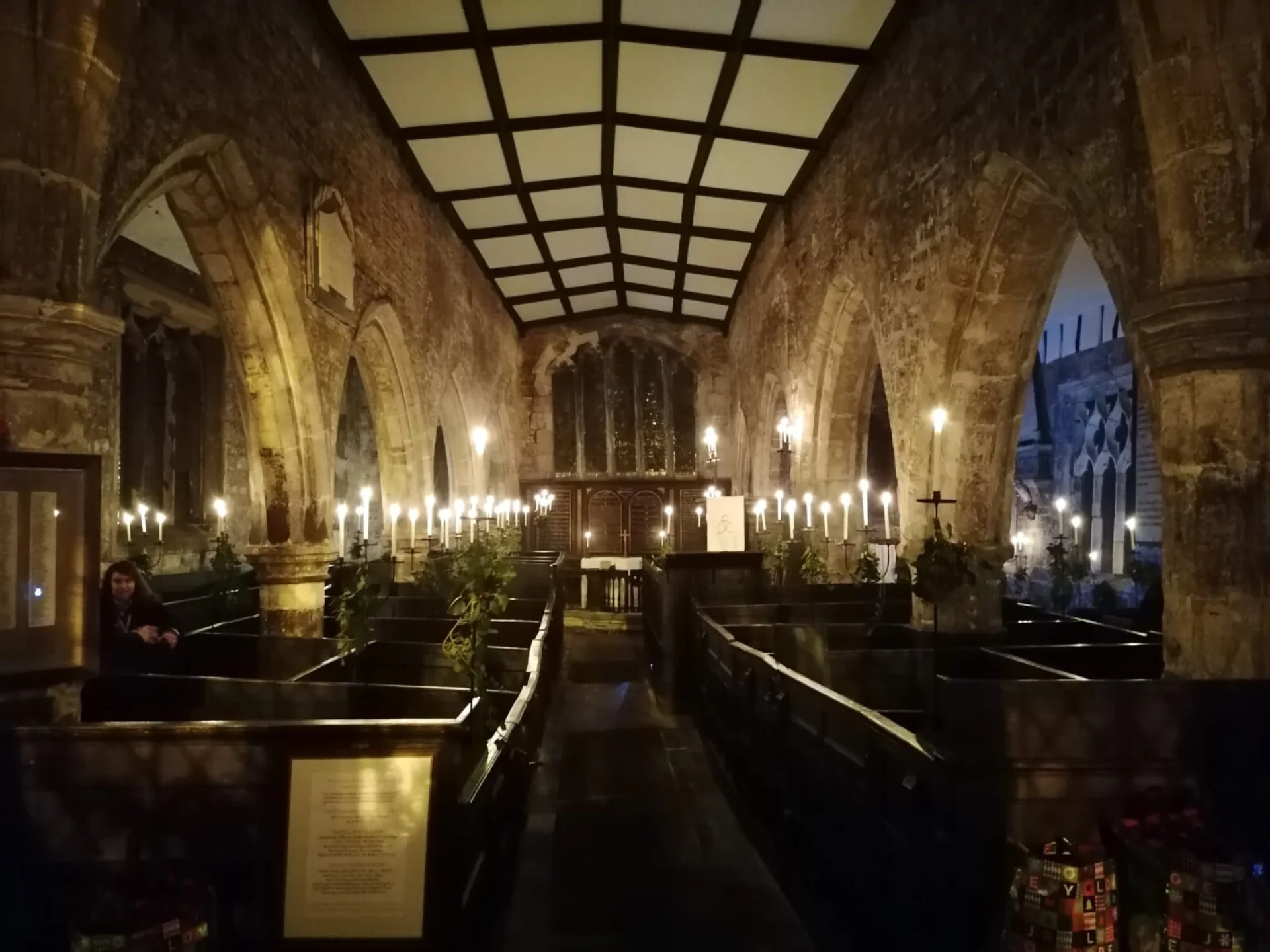 Dark interior of Holy Trinity Goodramgate showing box pews and candles