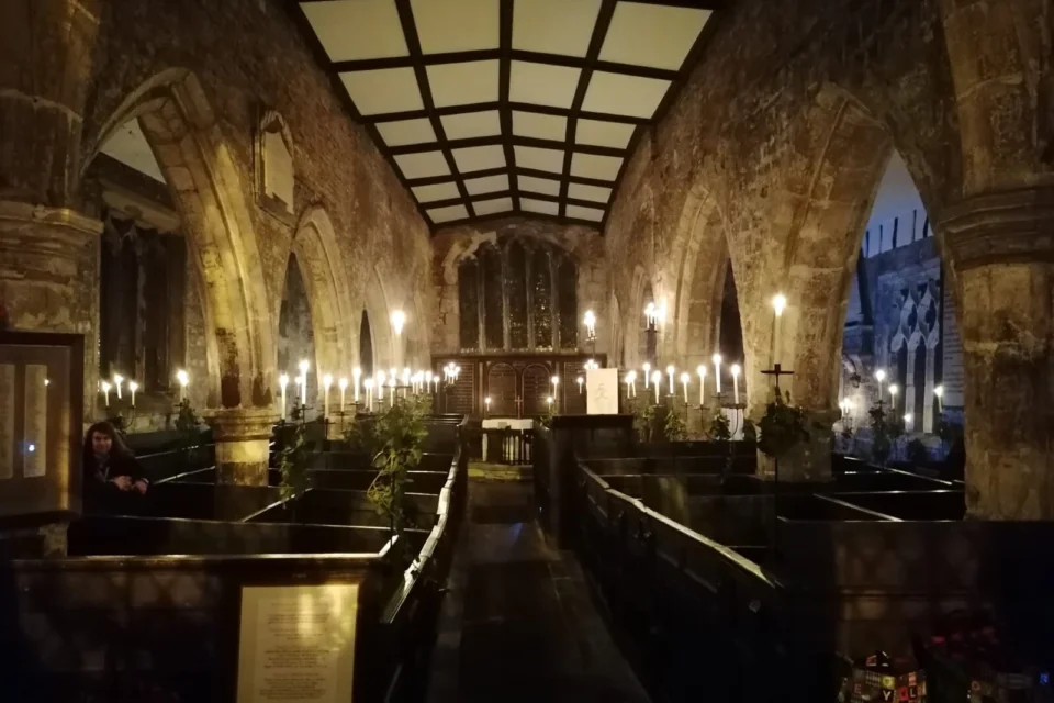 Dark interior of Holy Trinity Goodramgate showing box pews and candles