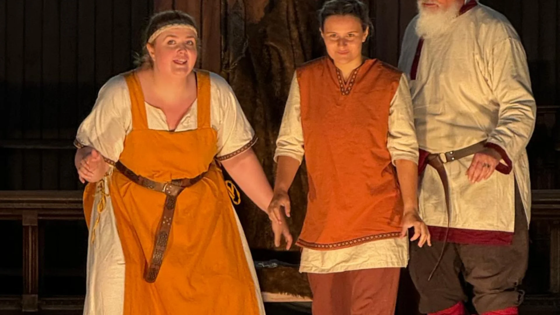 Three actors in viking costume stand next to each other, one is telling a story and the other two look full of excitement into the audience.
