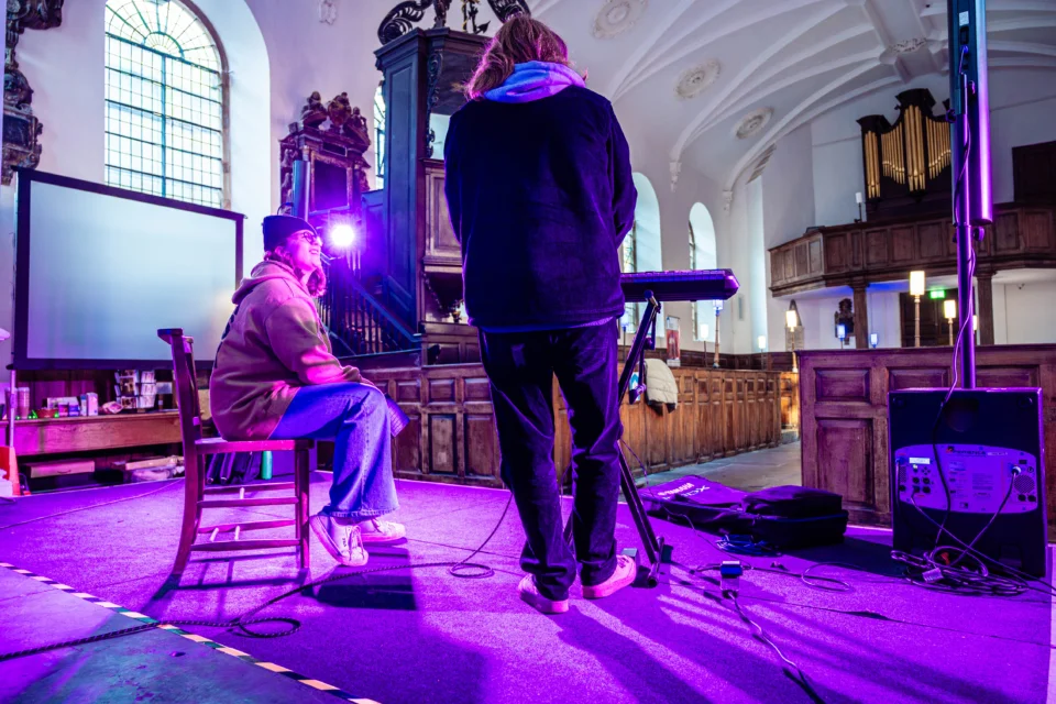 looking out from the stage in St Swithuns one performer sits while the other stands with a keyboard