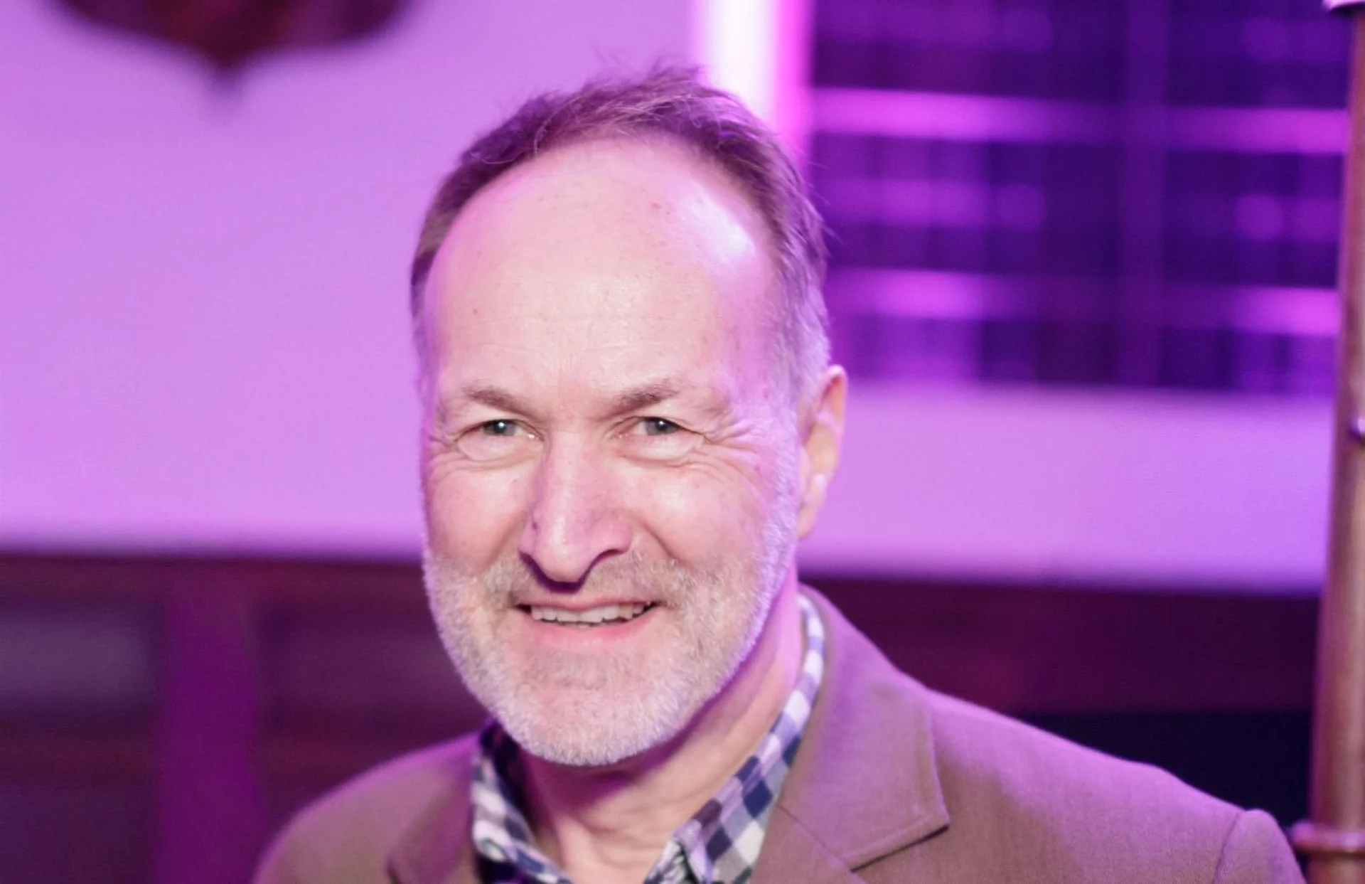 Image of a man in a camel coloured suit at an event.