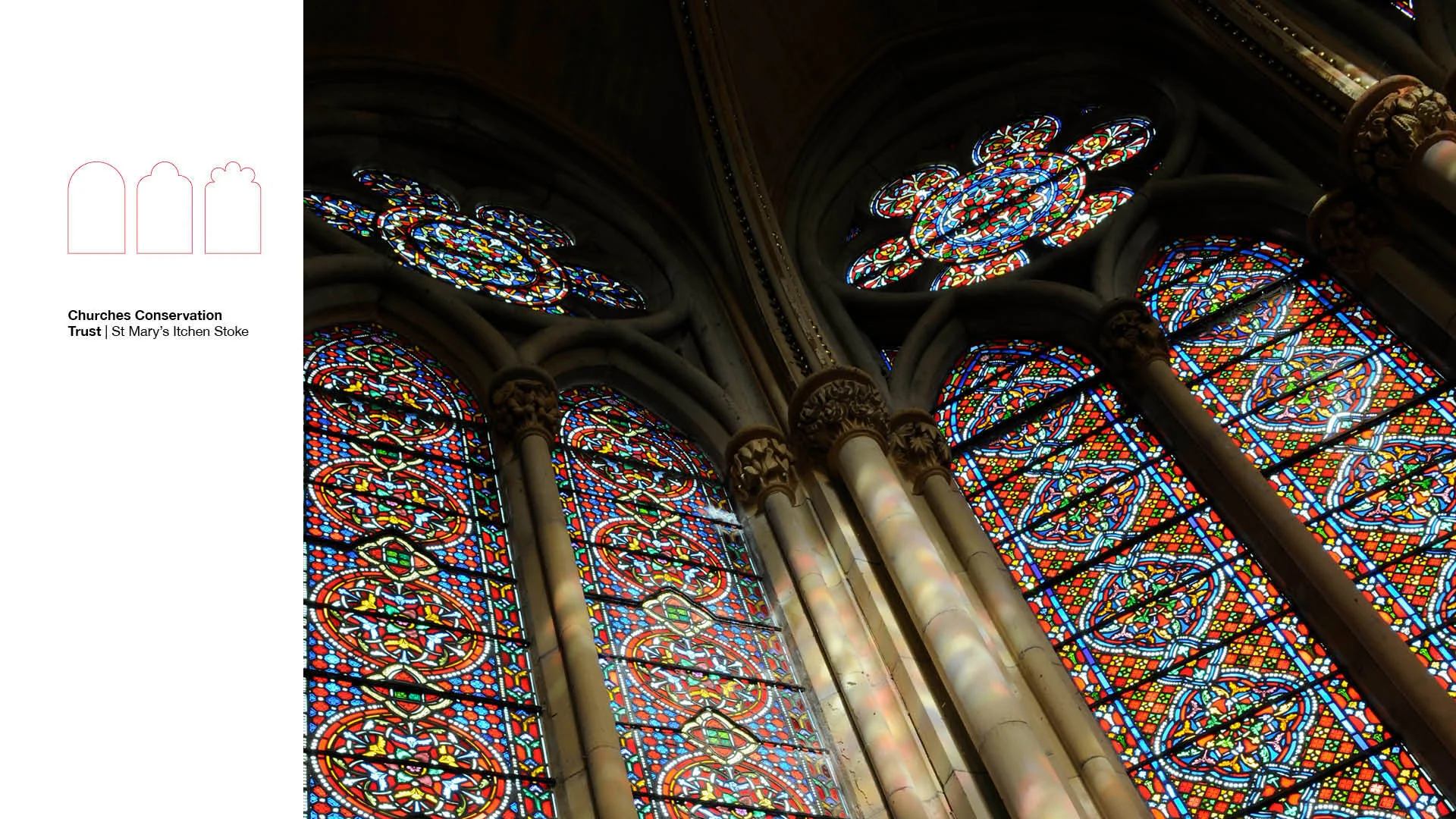 Close view of ornate stained glass windows with vivid coloured patterns and stone tracery.