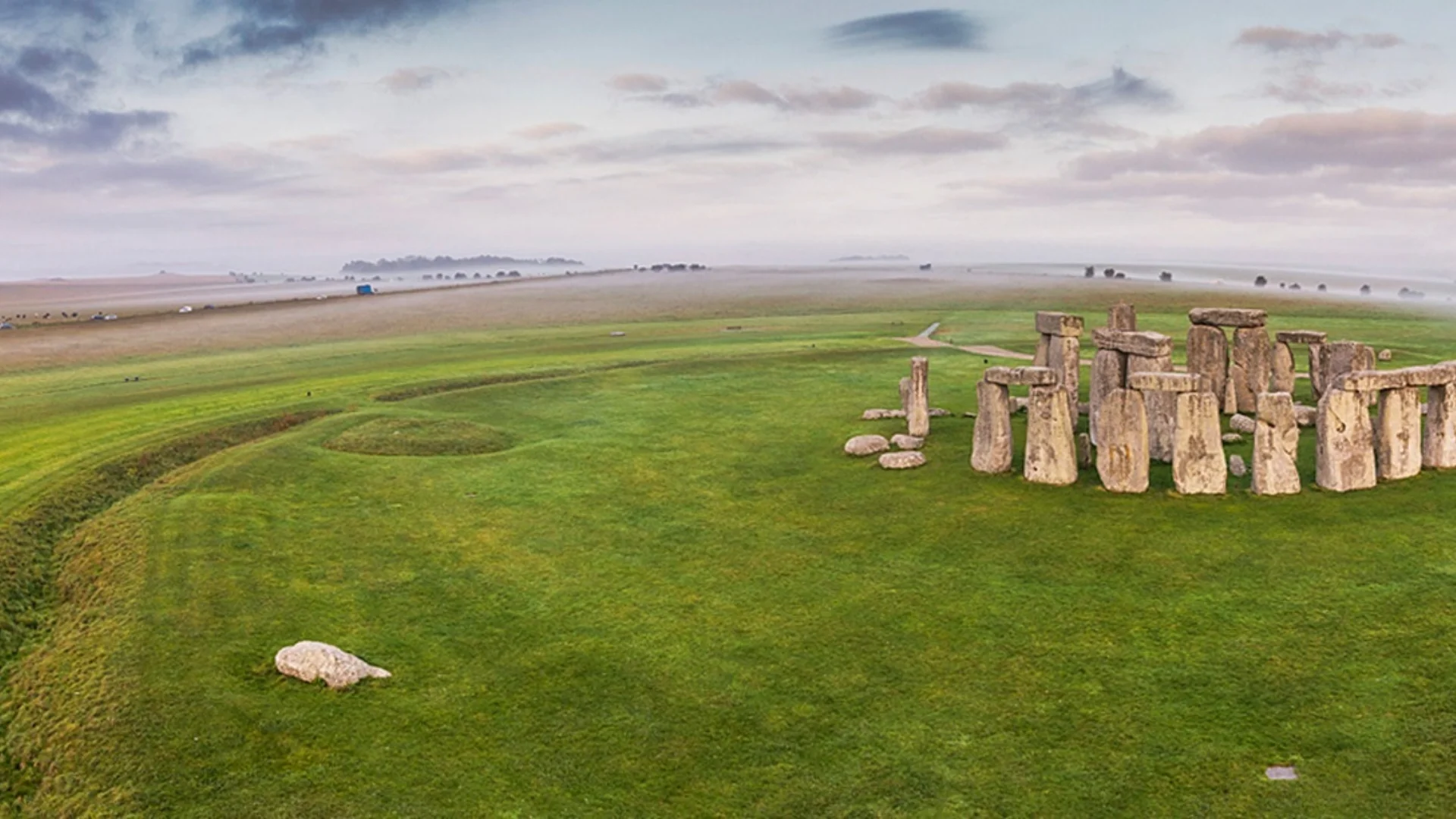 Panoramic wideshot with stone circle on right on grass with to the left fields in background