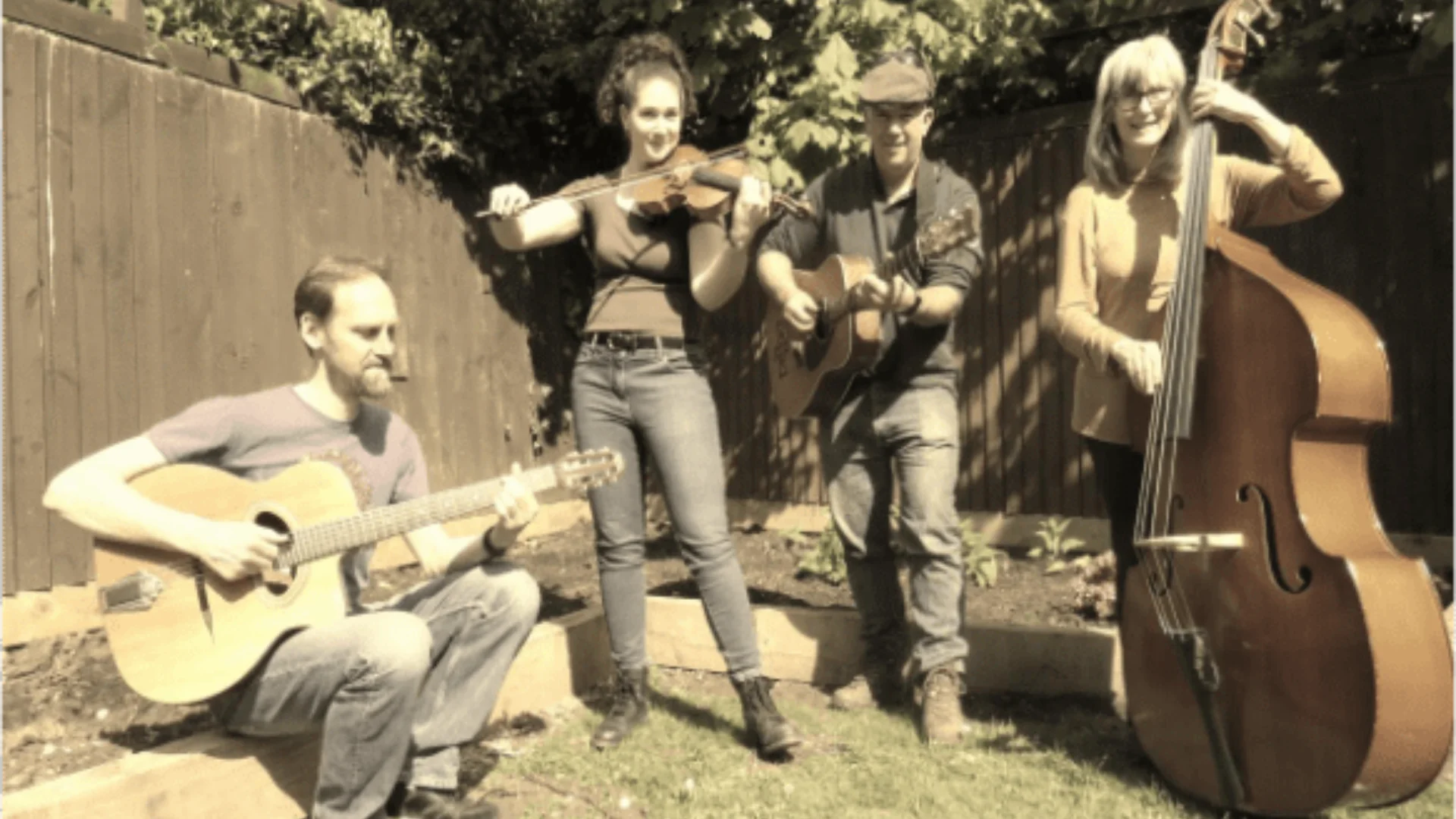 Four string musicians playing outside in garden