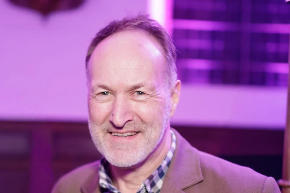 Image of a man in a camel coloured suit at an event.