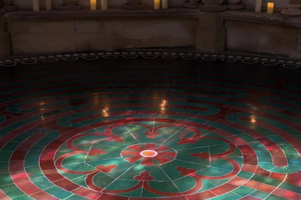 Labyrinth surrounded by candles and lit up with sunlight form the windows.