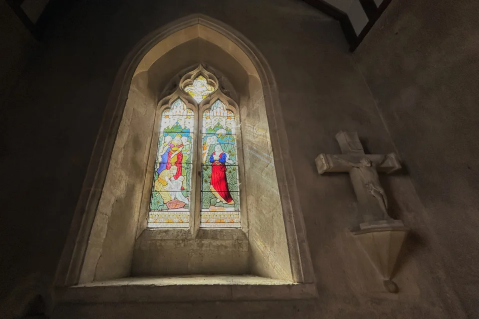 Stained glass window with a stone cross mounted to the right hand side