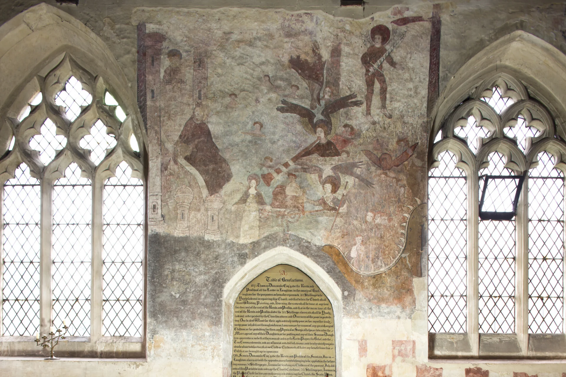 Photograph of a medieval doom wall painting at Broughton, showing the entrance to hell as a fish like monster with sharp teeth swallowing the souls of the damned, the archangel Michael weighing souls with the Virgin Mary next to him intervening on behalf of the deceased, several angels are blowing trumpets.