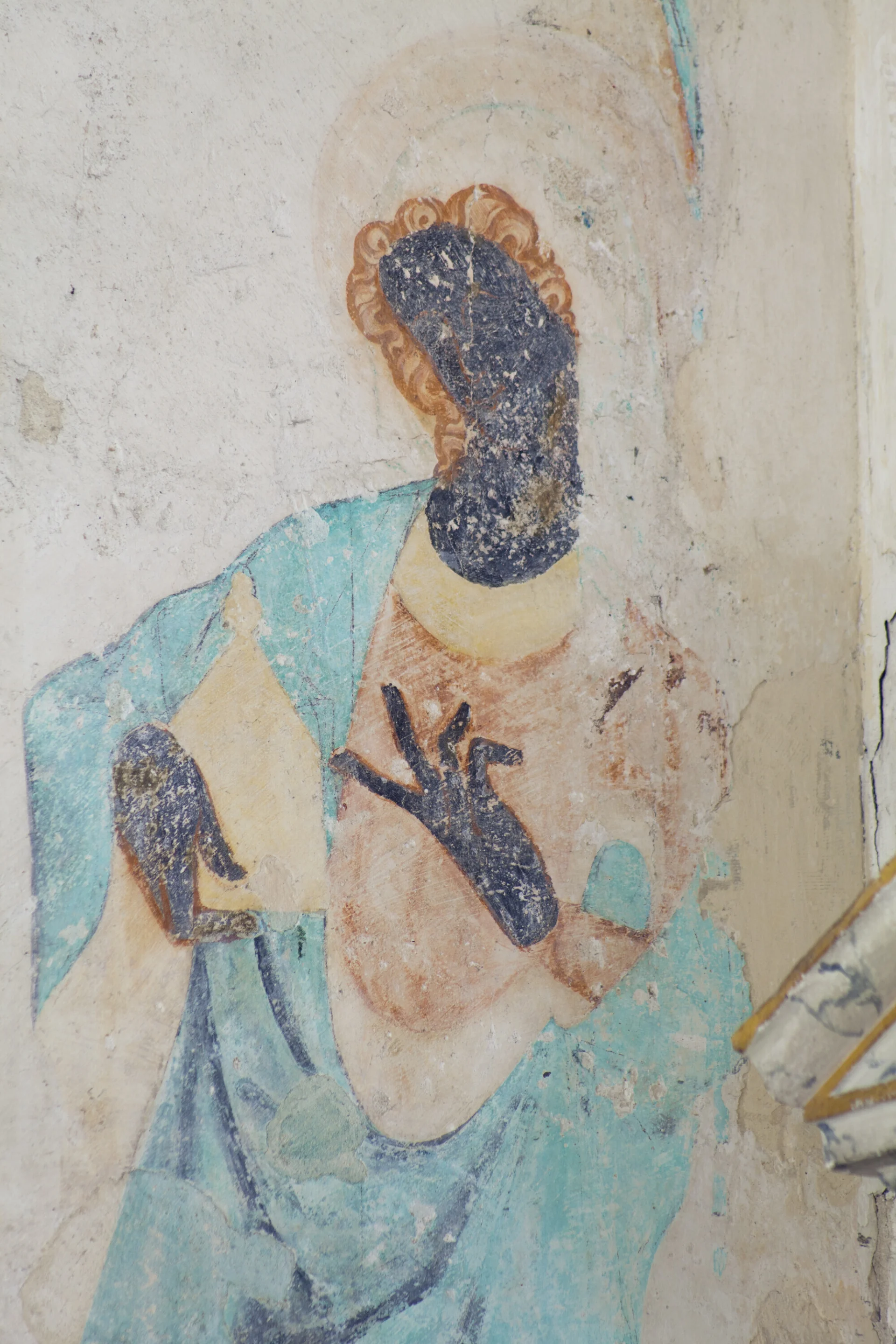 Wall painting of Mary Magdalene with her ointment jar. She wears red and turquoise robes, has red hair and wears a veil. Her face and hands are black.