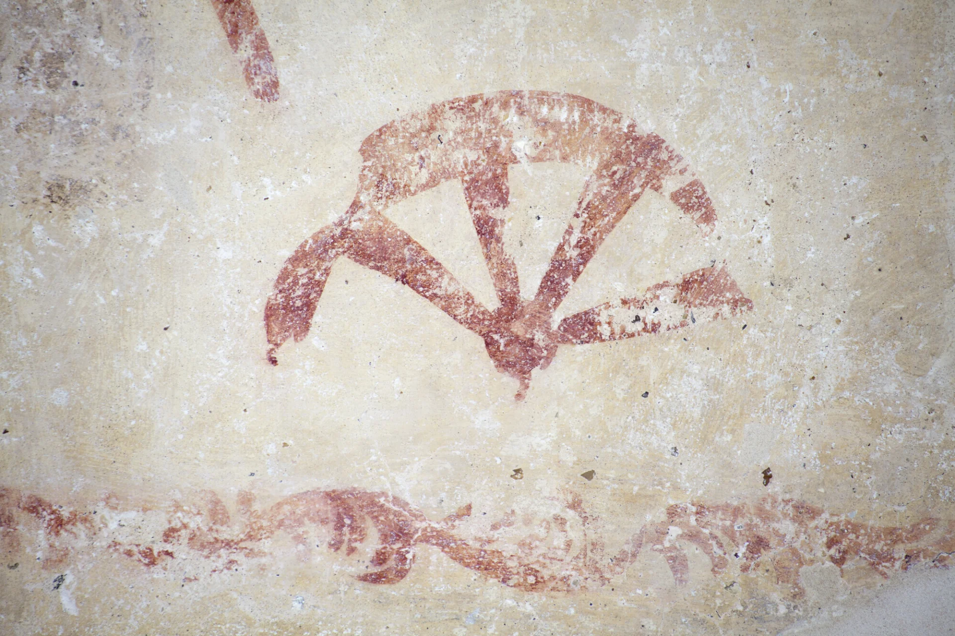 A red paint remnant of a depiction of St. Catharine's wheel as part of a medieval wall painting at St. John's Duxford.