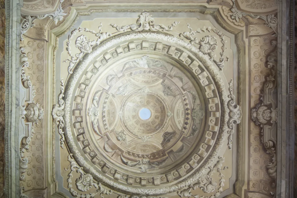 Ceiling painted to look like a classical temple ceiling with a cupola in the centre that opens to show a circle of blue