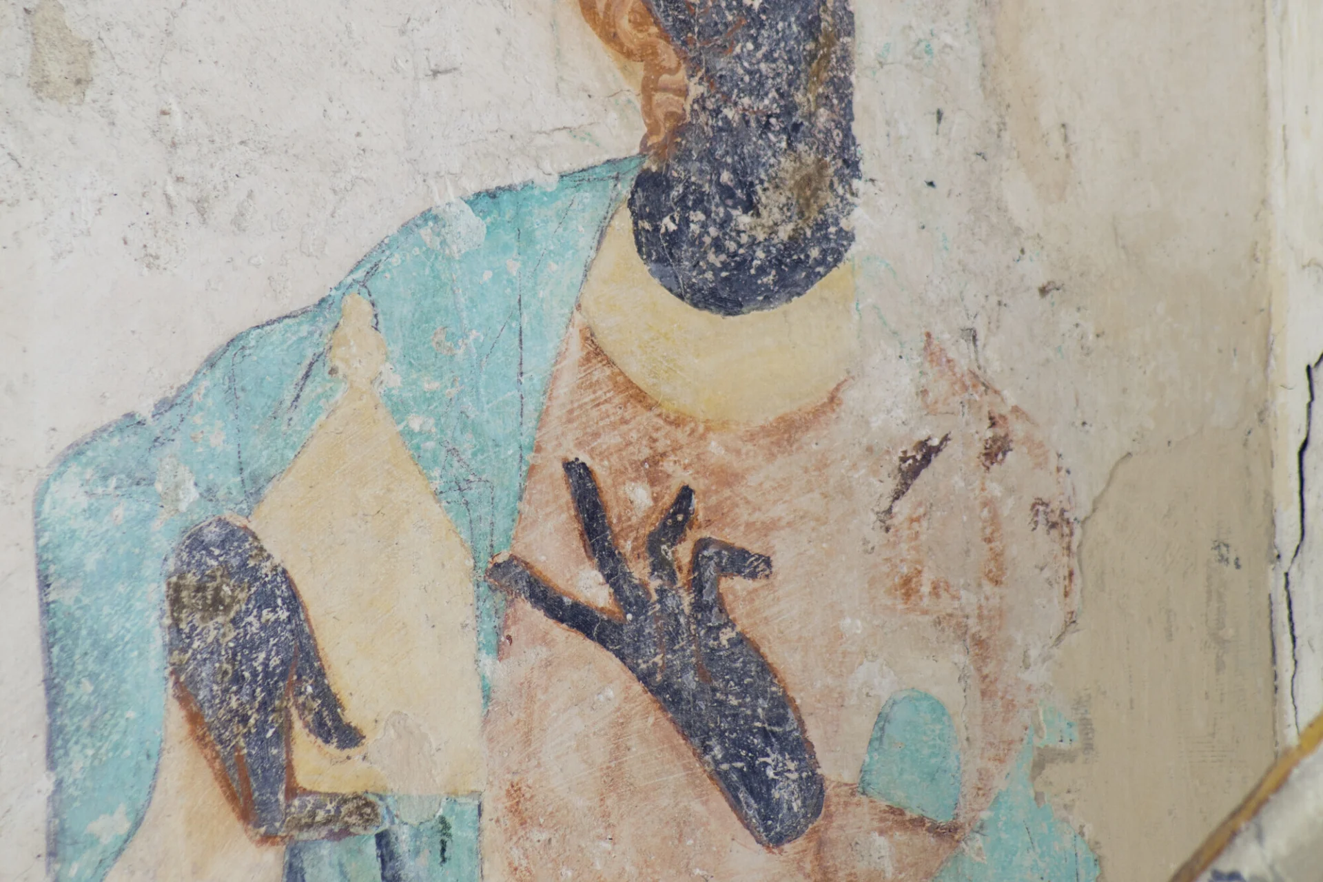 Wall painting of Mary Magdalene with her ointment jar. She wears red and turquoise robes, has red hair and wears a veil. Her face and hands are black.